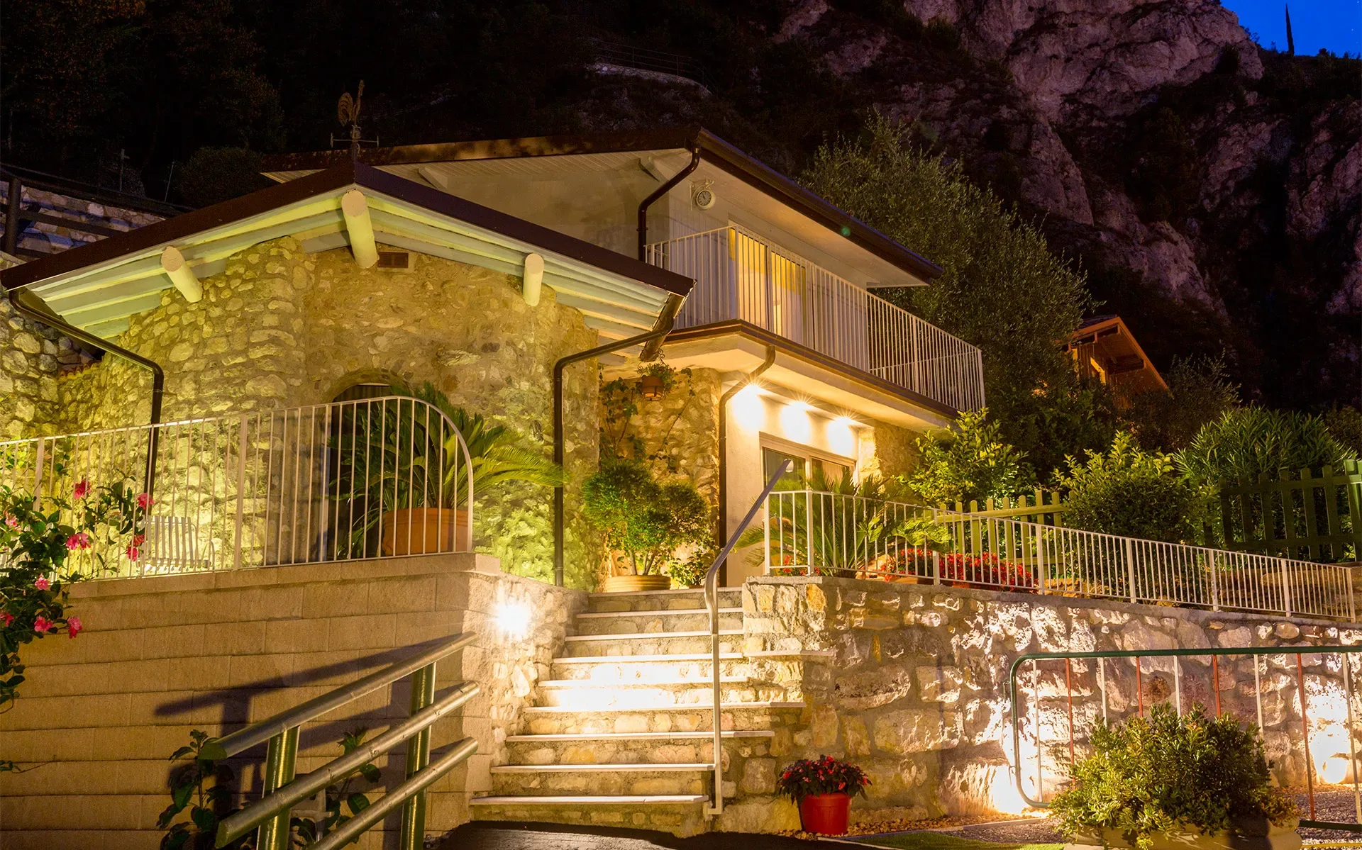 Steinhaus mit beleuchteten Terrassen bei Nacht in Hanglage