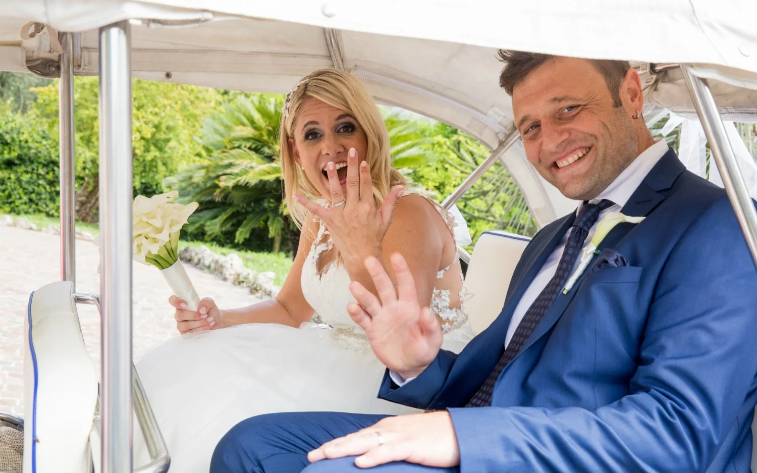 Smiling bride and groom show wedding rings in the car