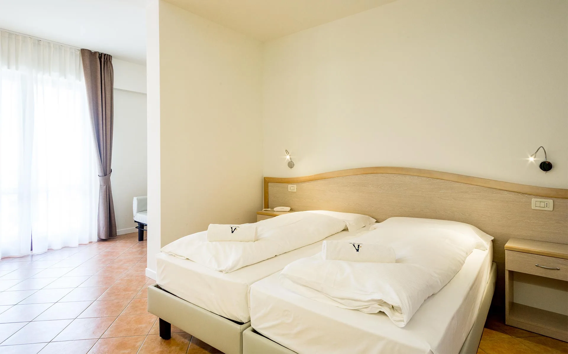 Camera d'hotel luminosa con due letti singoli e arredamento moderno