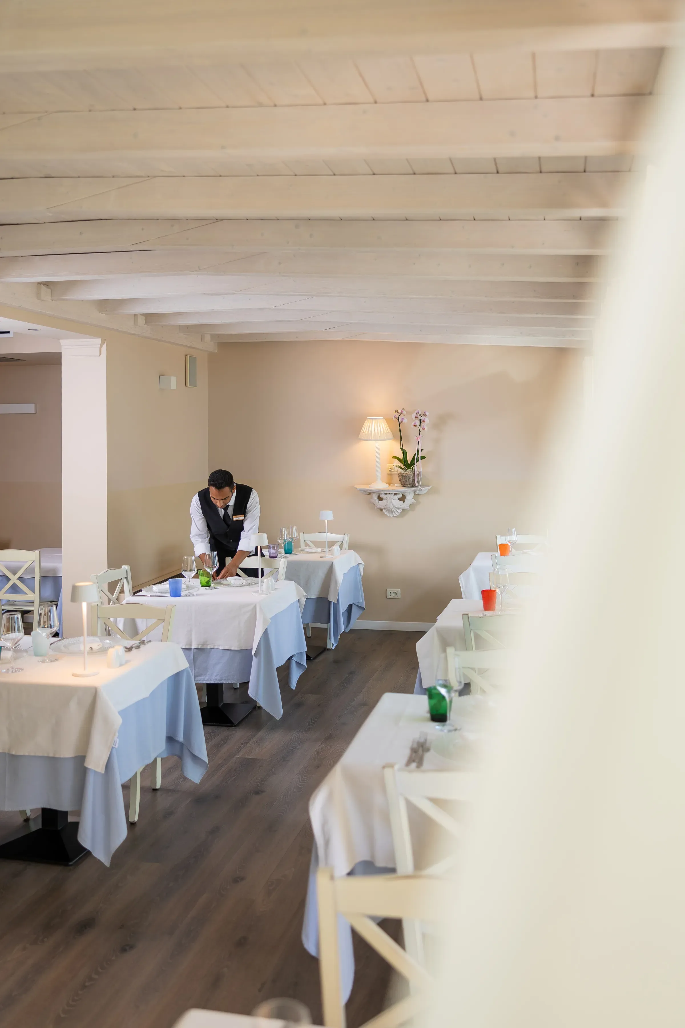 Cameriere che prepara i tavoli in un elegante ristorante vuoto