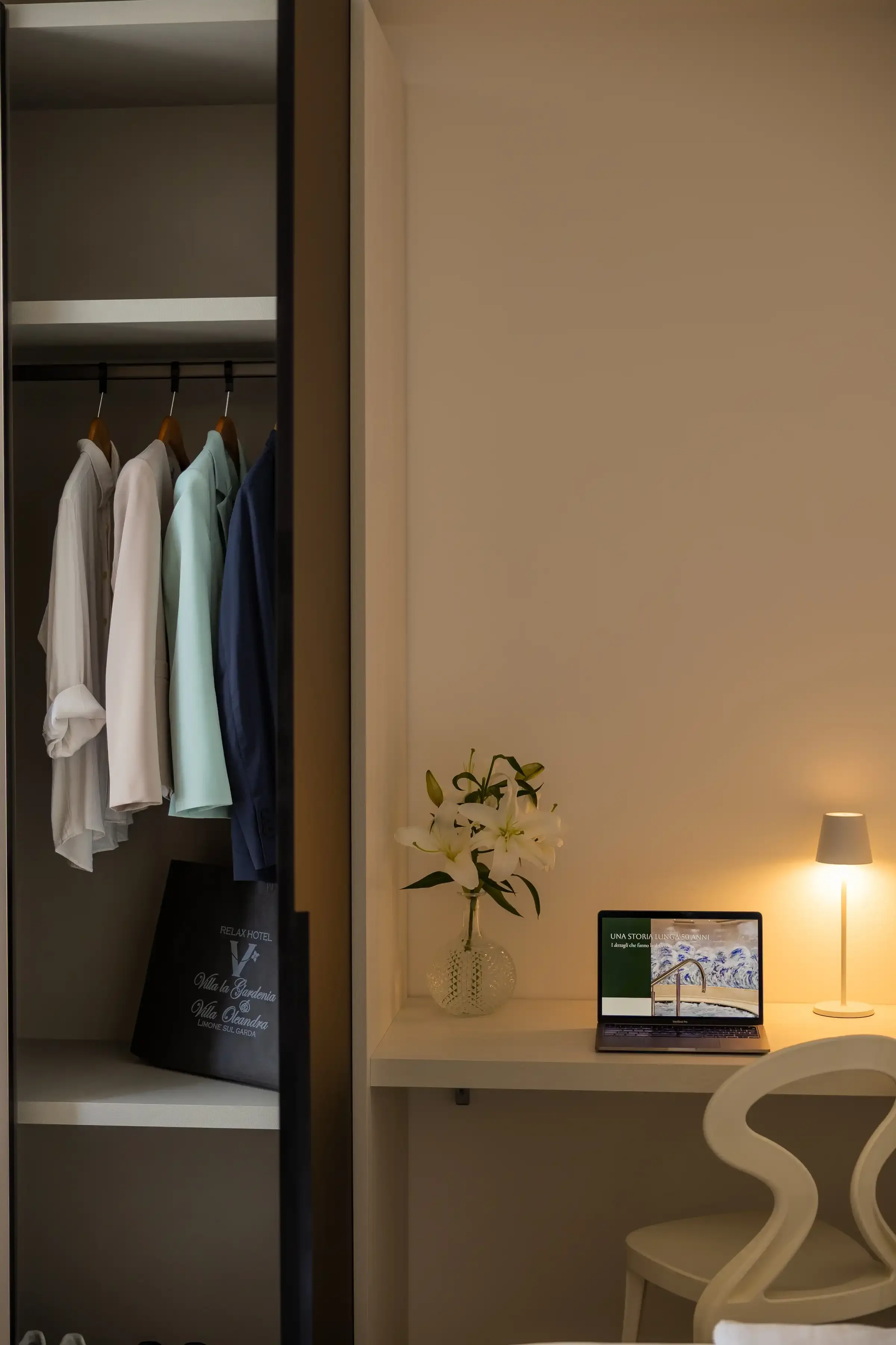 Chemises suspendues à côté d’un bureau avec ordinateur portable allumé