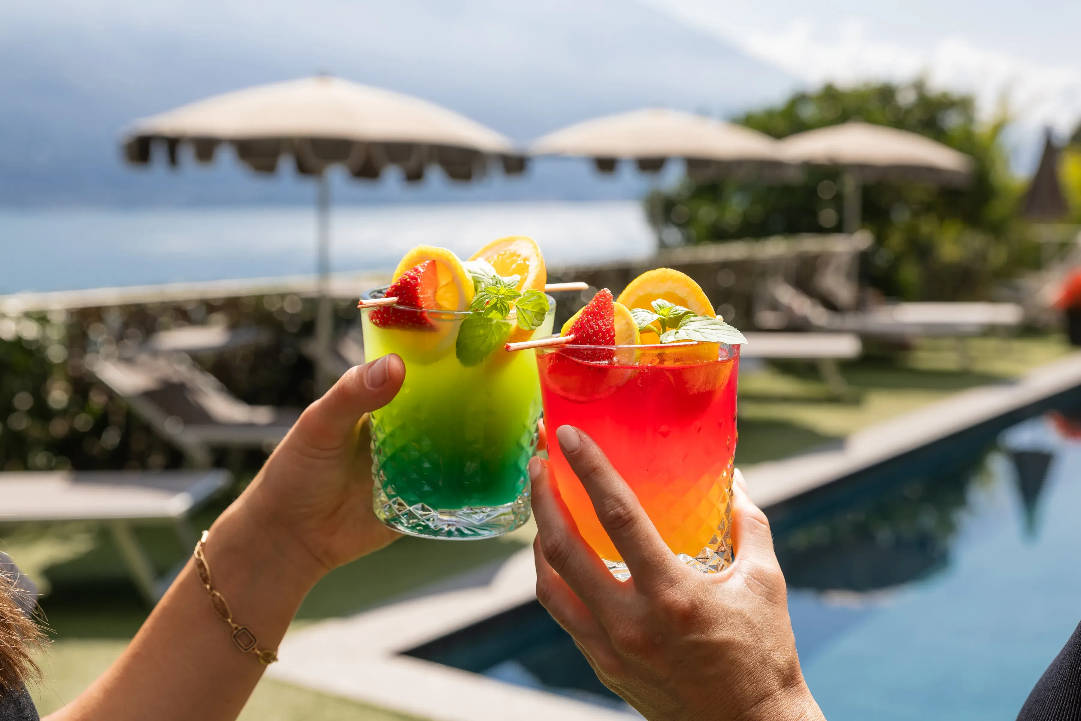 Due cocktail colorati con frutta fresca a bordo piscina