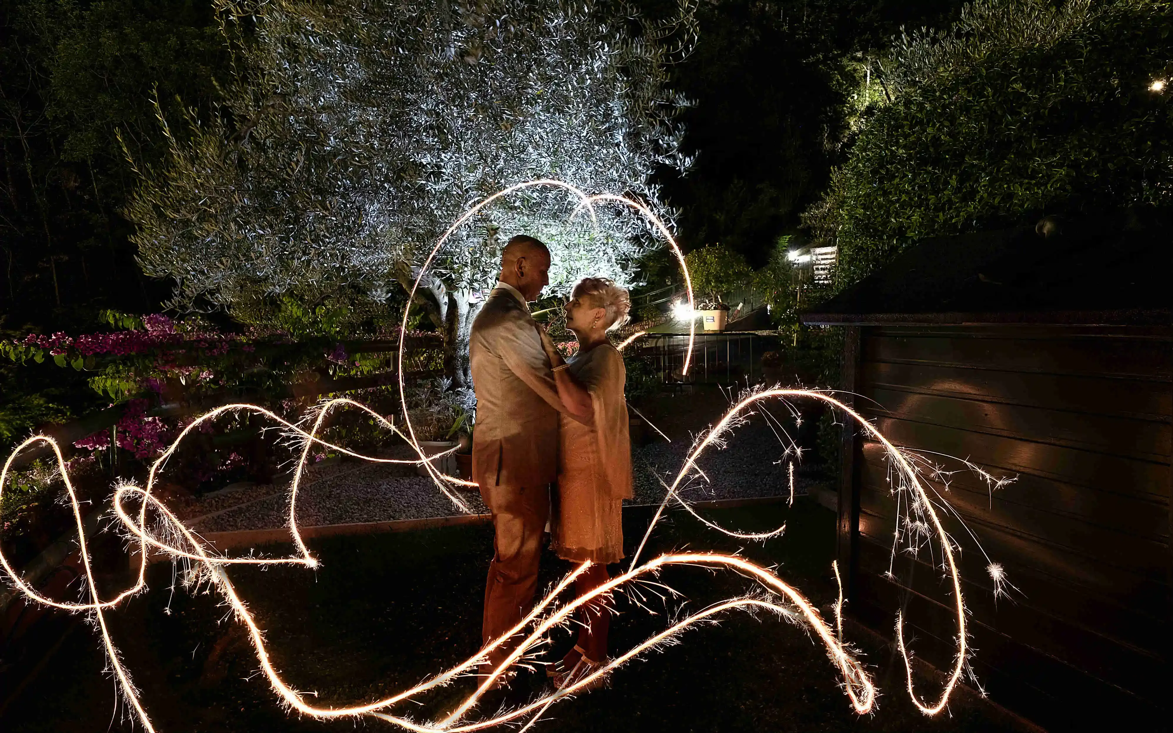 Couple embracing surrounded by sparklers in a nighttime garden