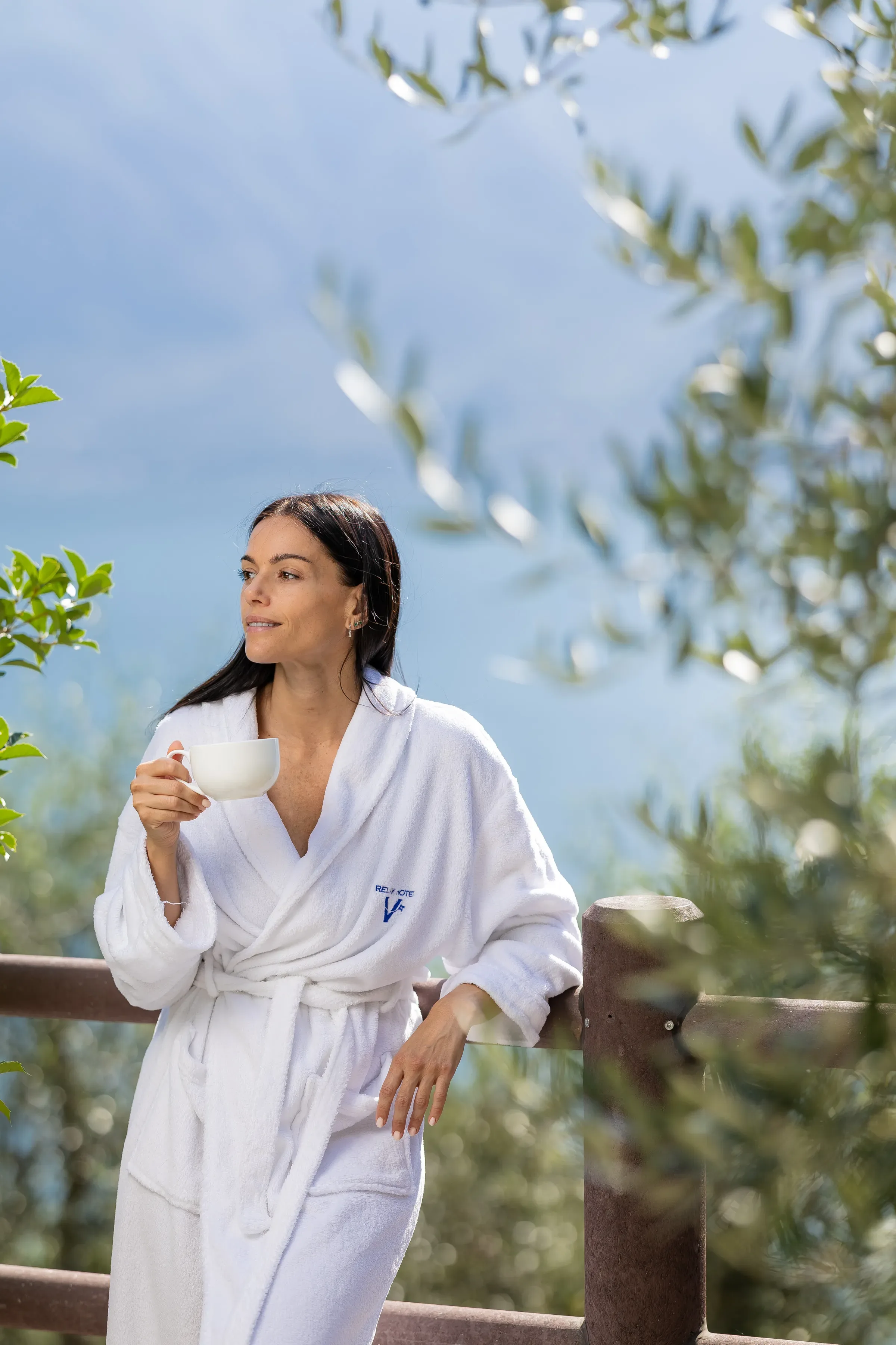 Donna rilassata in accappatoio che beve una tisana all'aperto