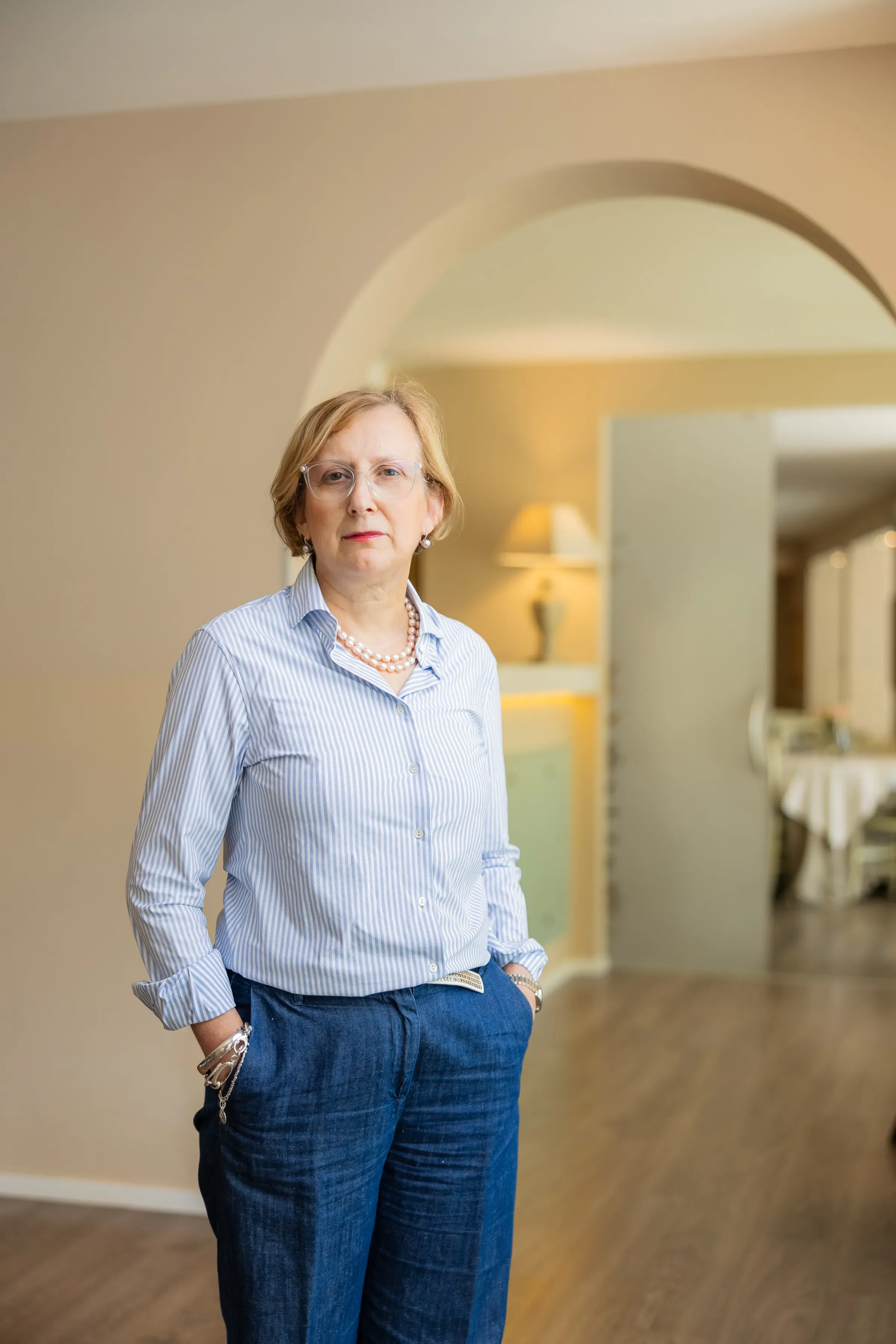 Donna matura con camicia a righe e pantaloni jeans in un interno elegante