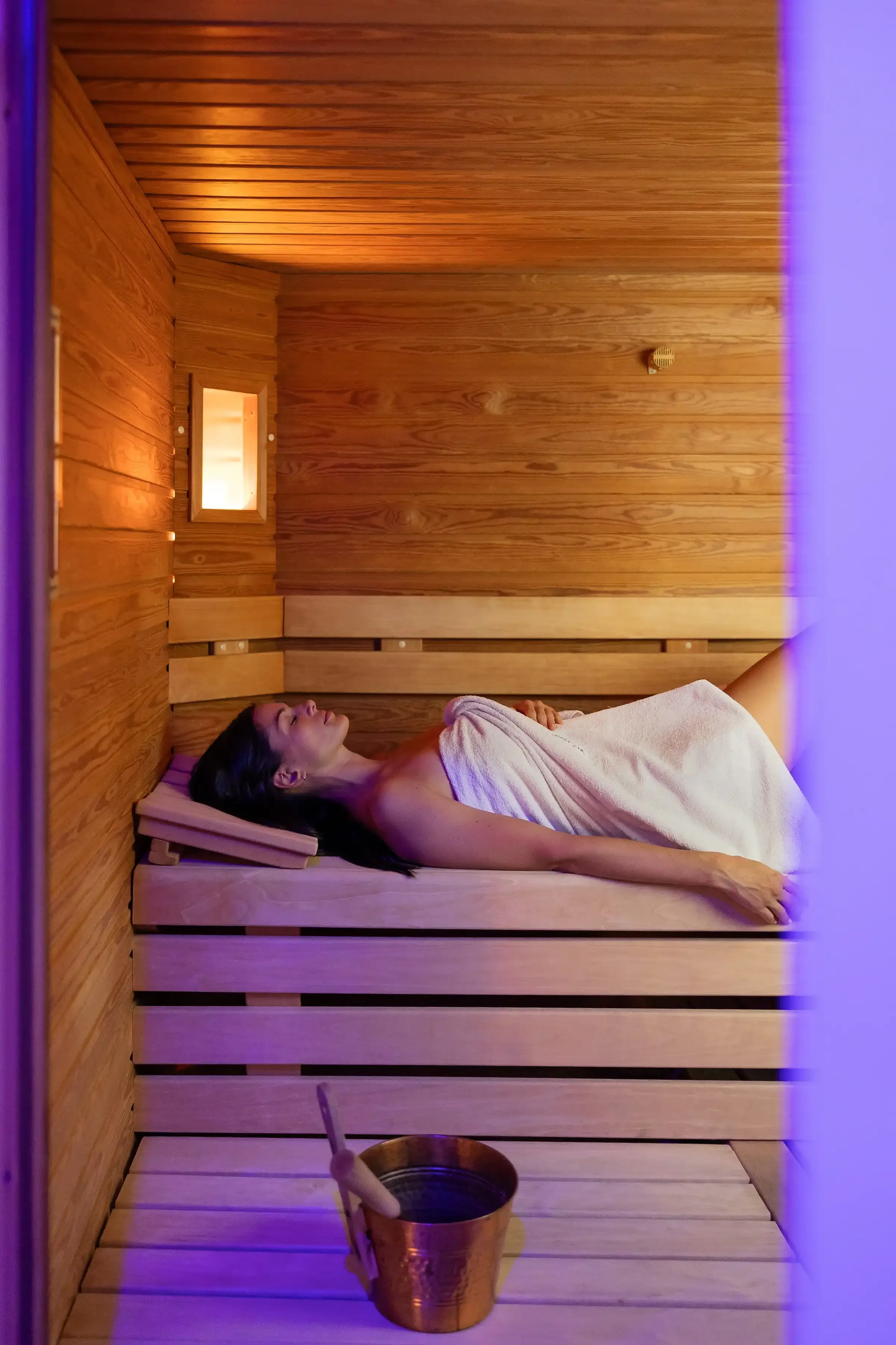 Donna rilassata distesa in sauna in legno