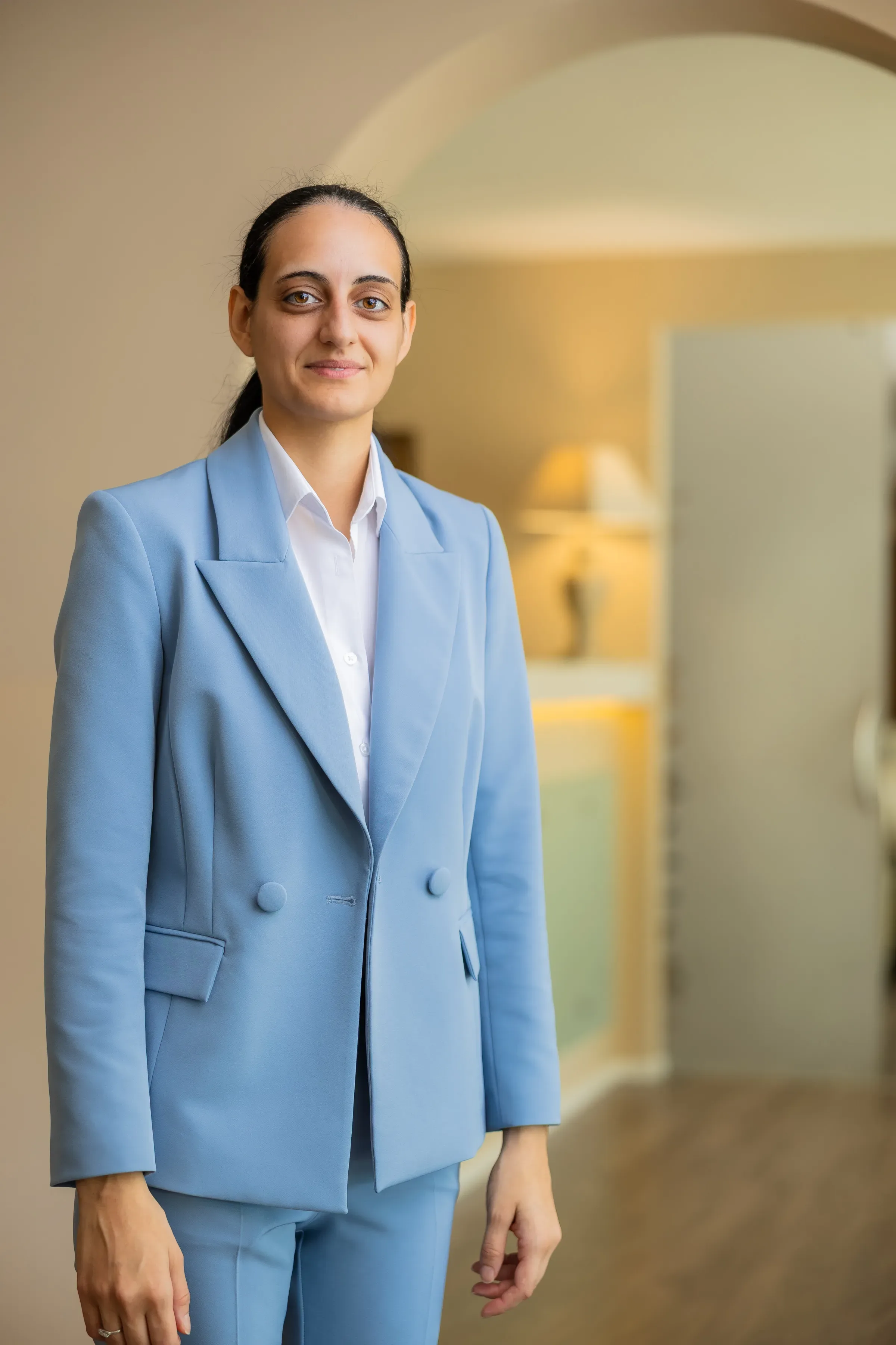 Donna sorridente in abito azzurro in un ambiente elegante