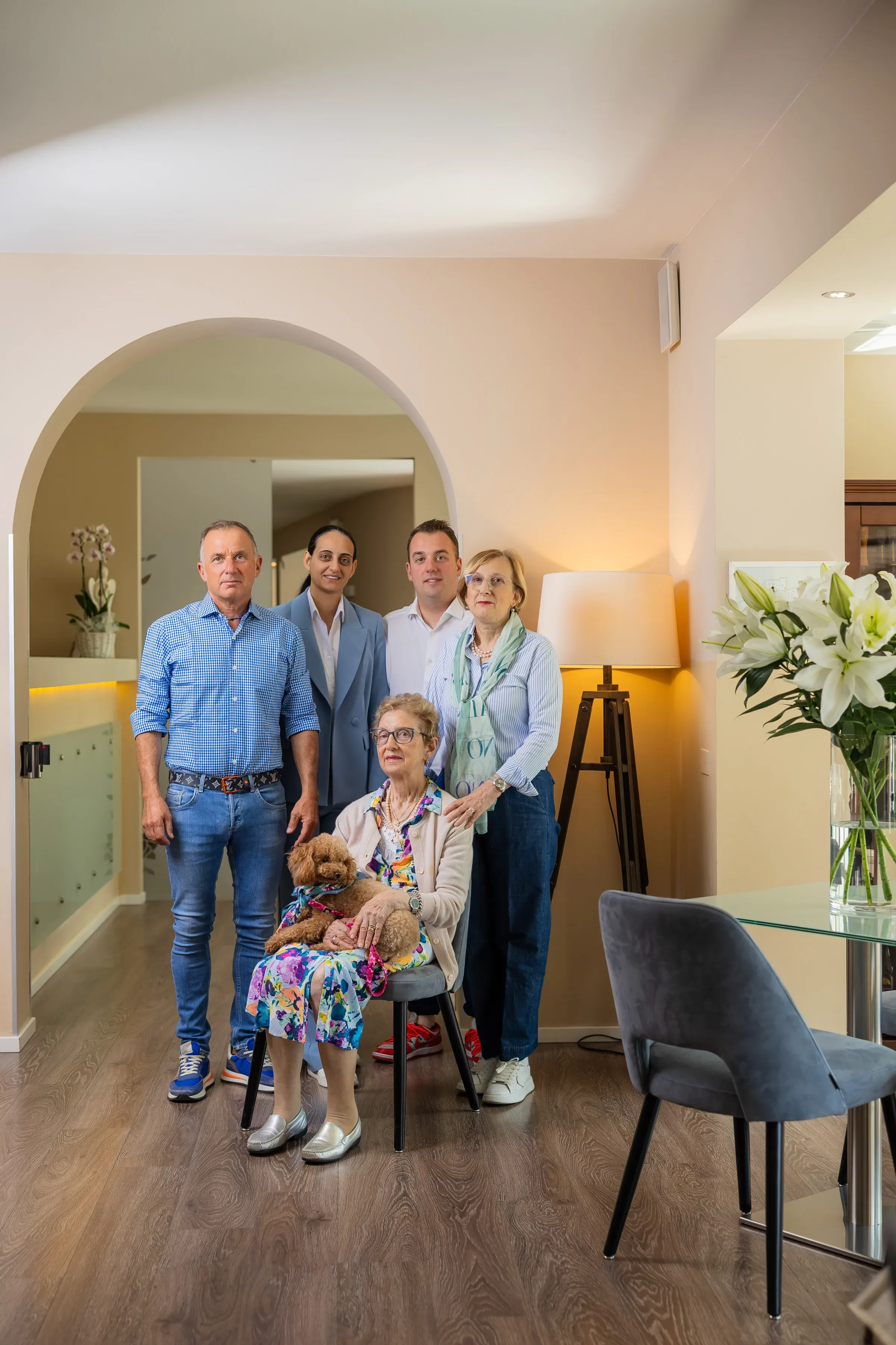 Famiglia con anziana seduta e cane in braccio in salone moderno