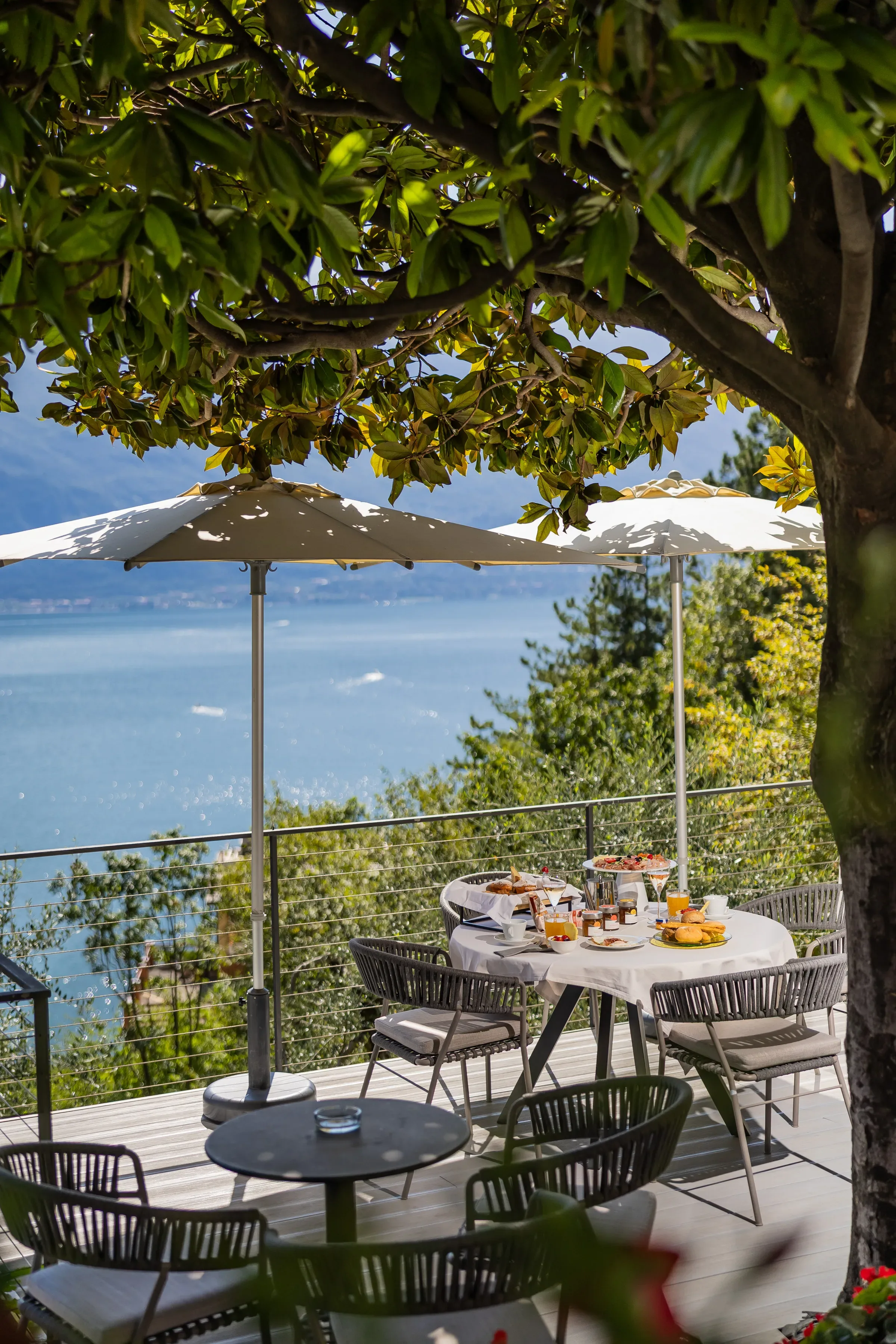 Frühstücksterrasse mit Seeblick und Sonnenschirmen