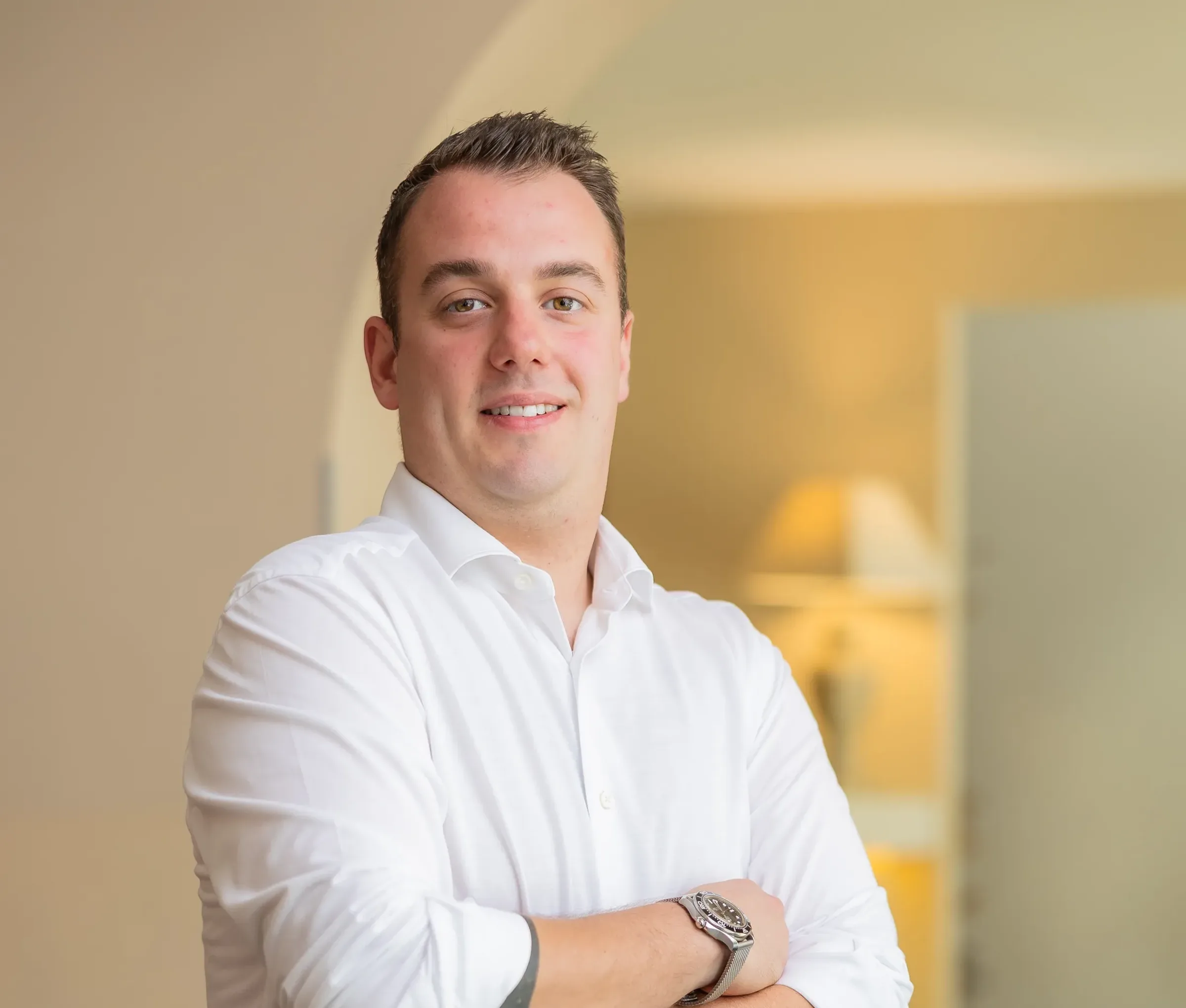 Homme souriant en chemise blanche, bras croisés