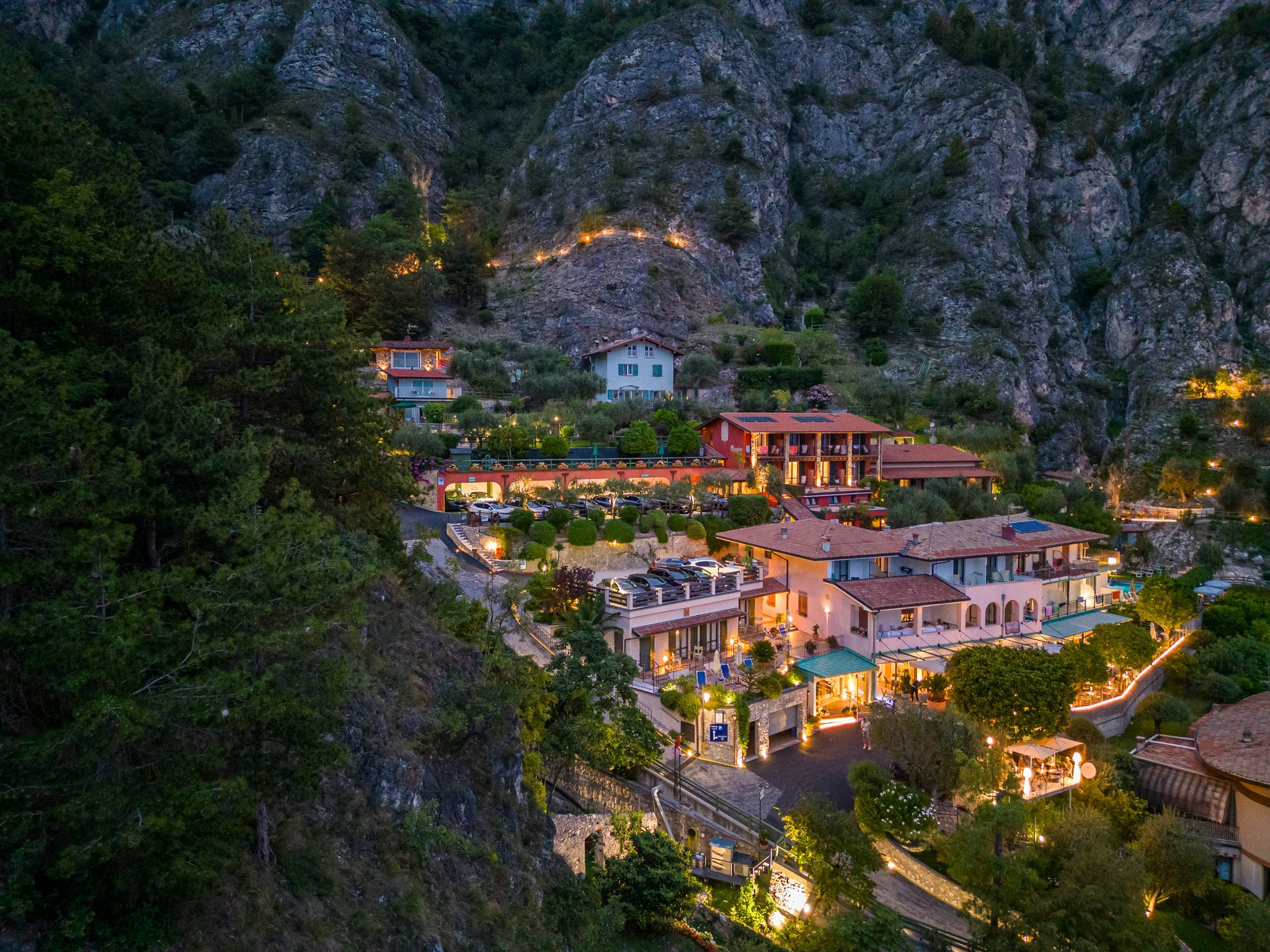 Hotel di montagna illuminato tra alberi e rocce al tramonto