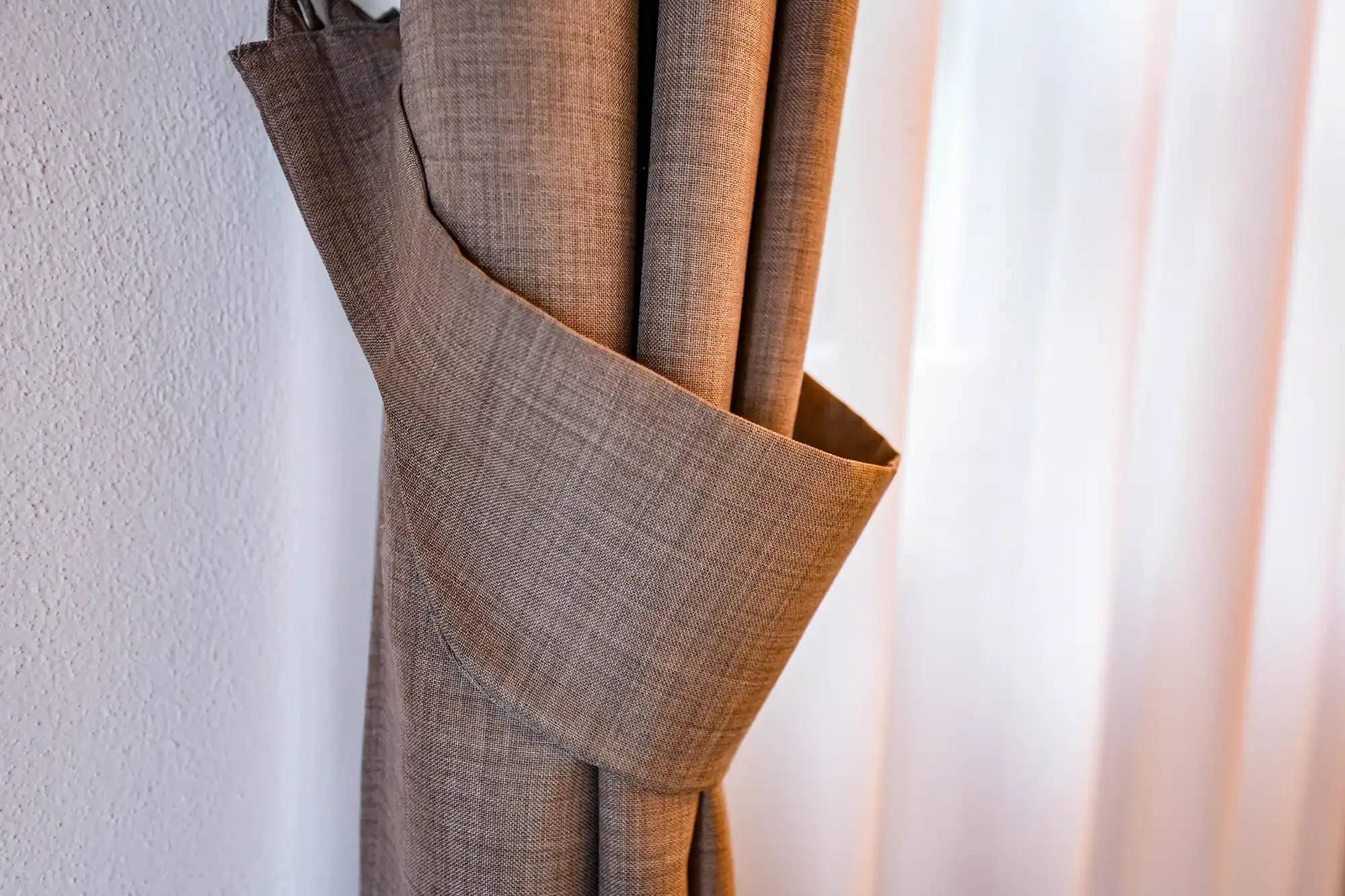 Rideau marron attaché avec une ceinture en tissu près d’une fenêtre