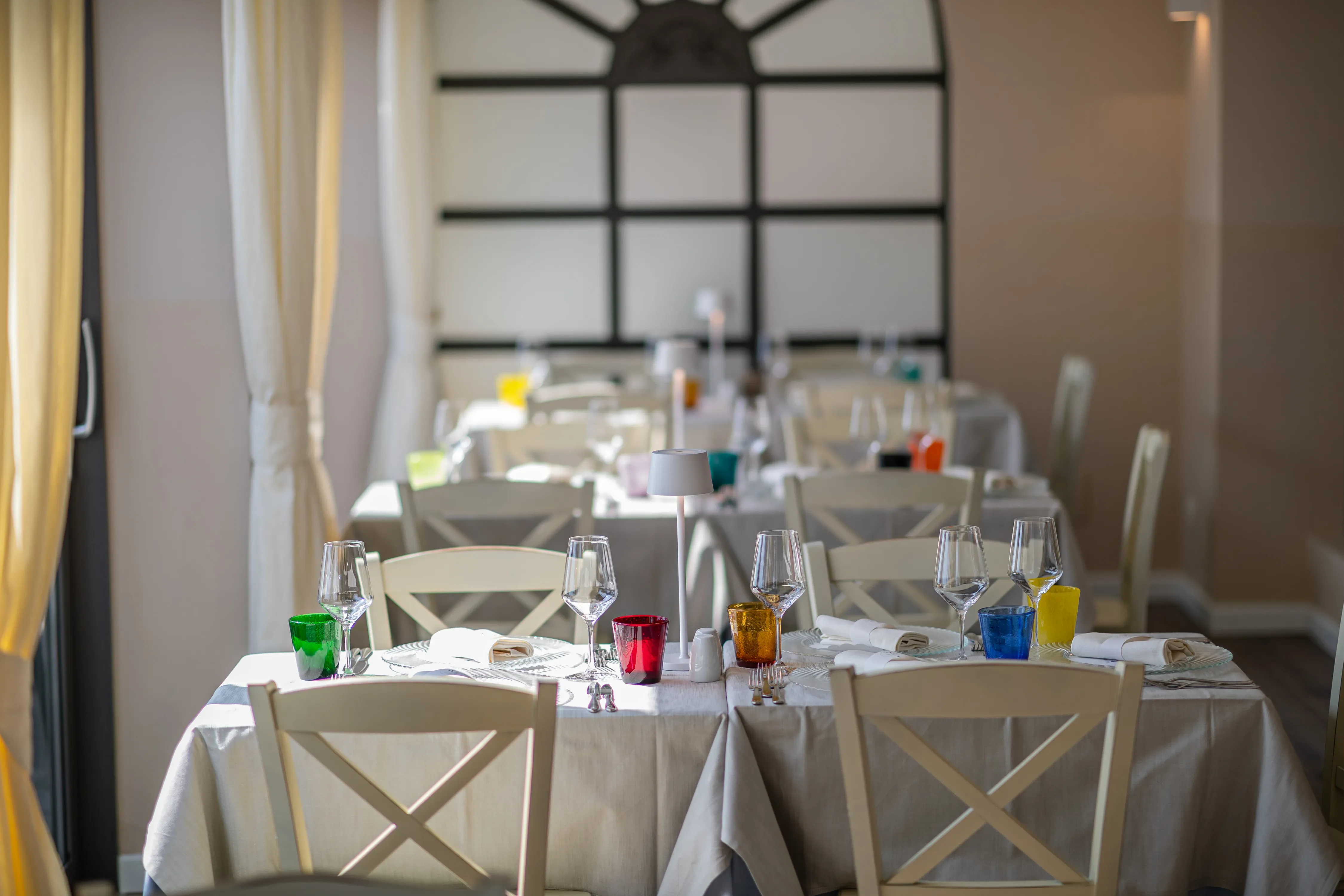 Sala ristorante elegante con tavoli apparecchiati e luce naturale