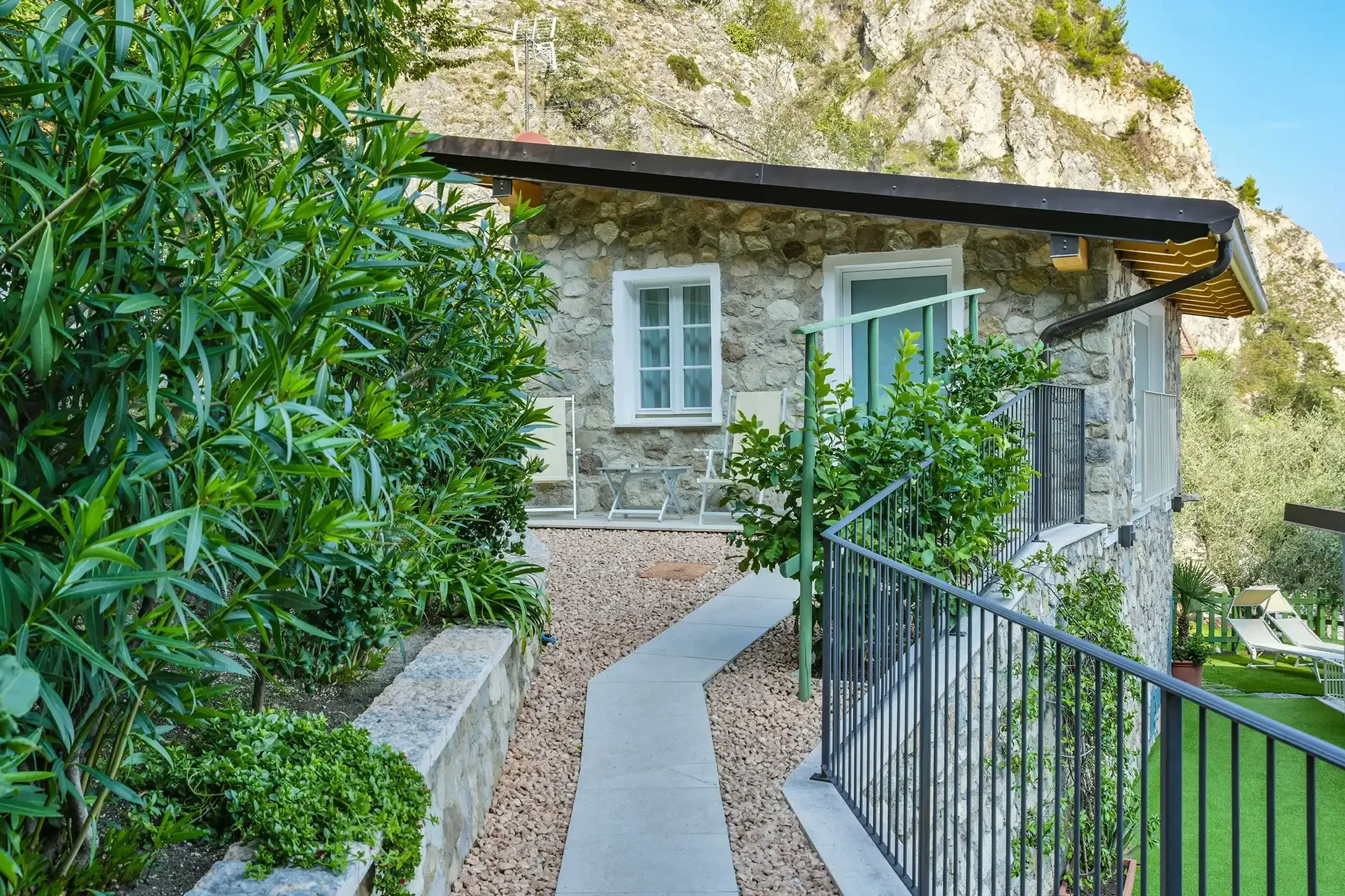 Stone house with garden path and green plants