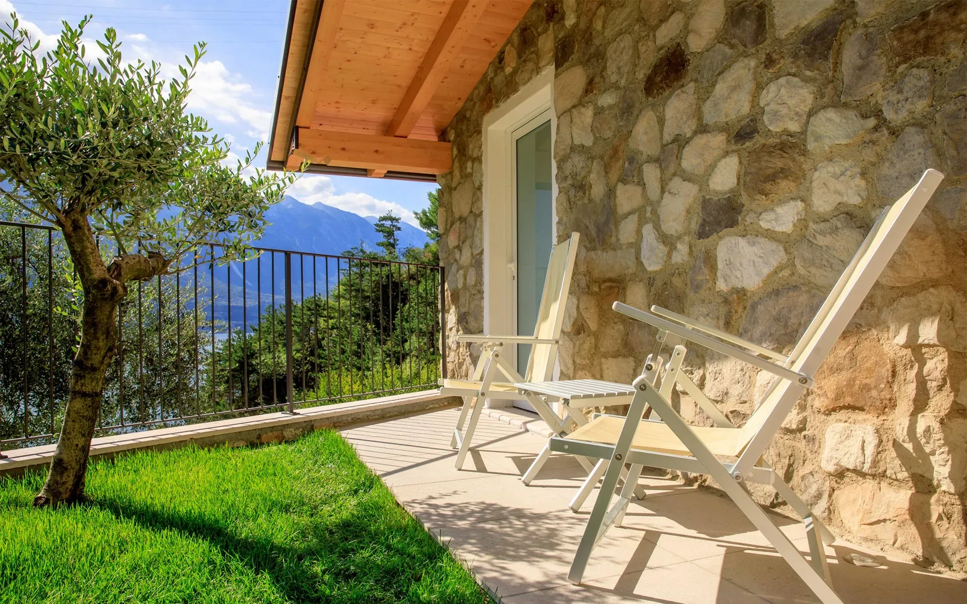 Terrazza soleggiata con sedie vista lago e montagne