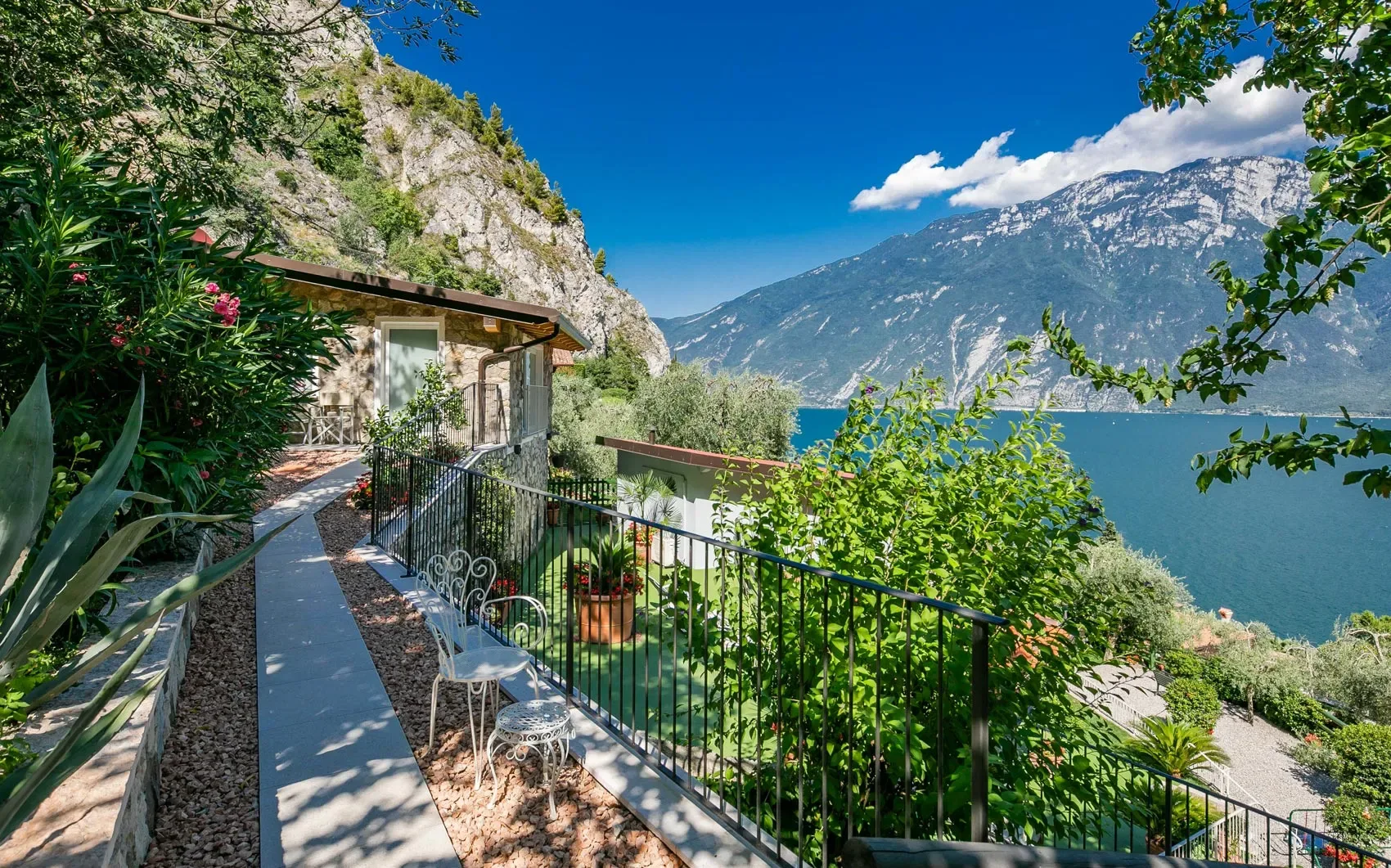 Sentiero con vista lago e casa in pietra tra le montagne