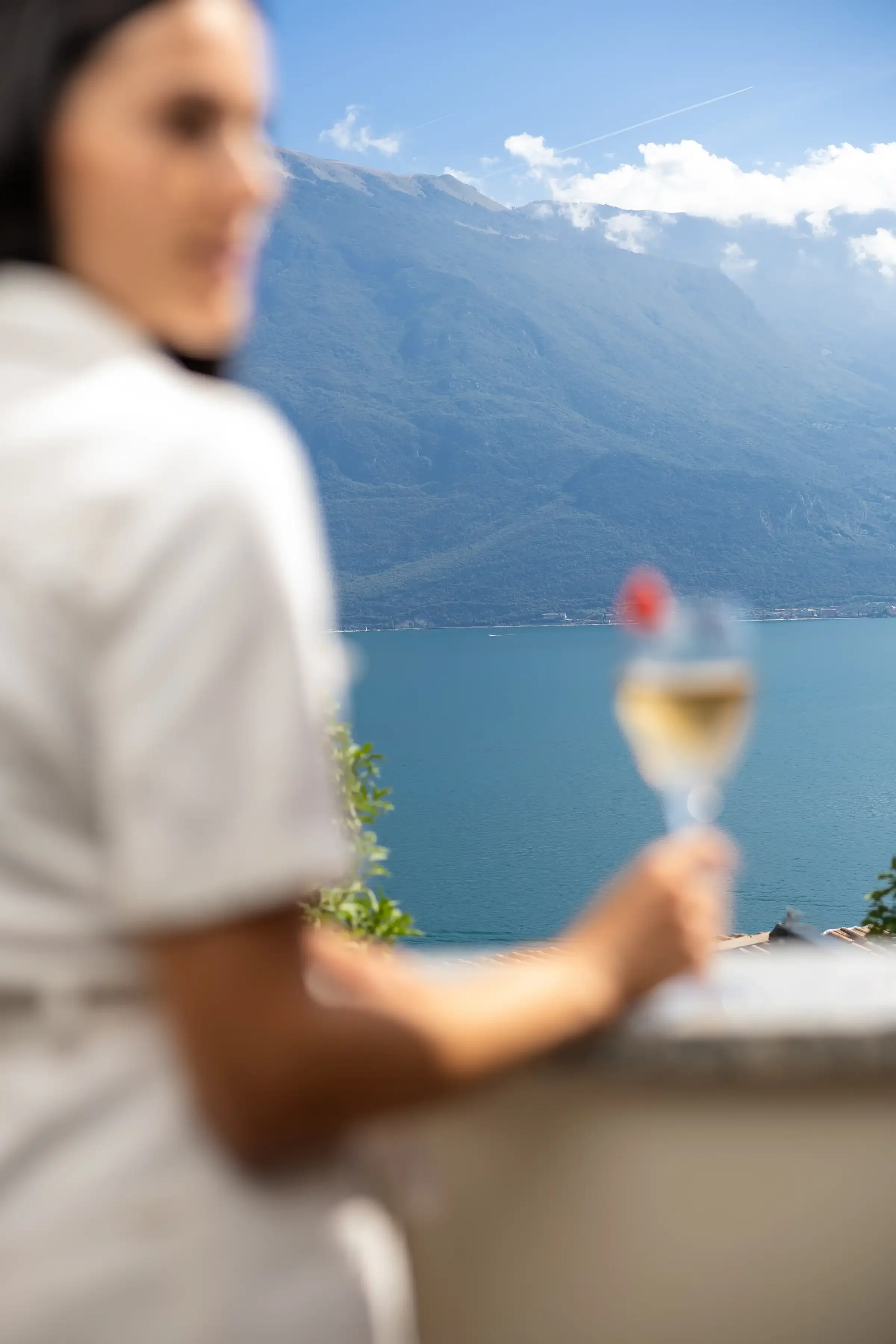 Femme tenant un verre de vin face au lac et montagnes
