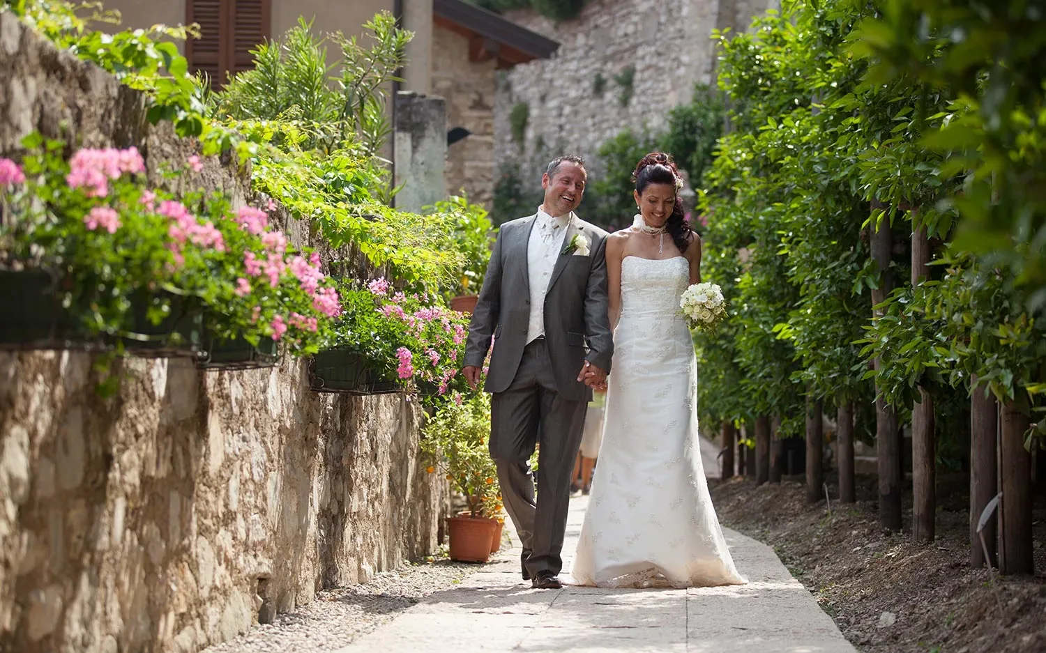 Happy wedding couple walking through blooming garden path