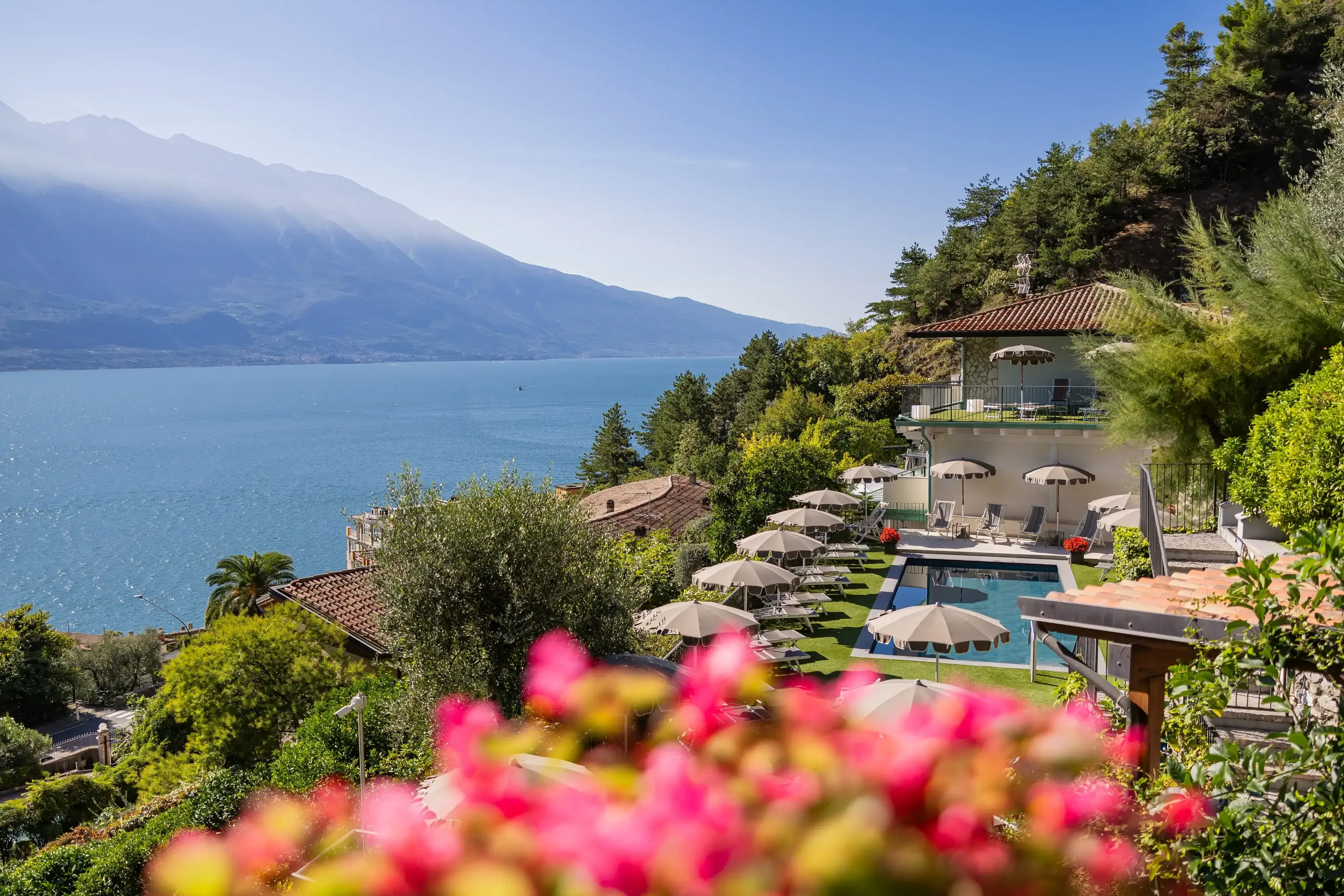 Widok na hotel z basenem, jeziorem i górami w tle