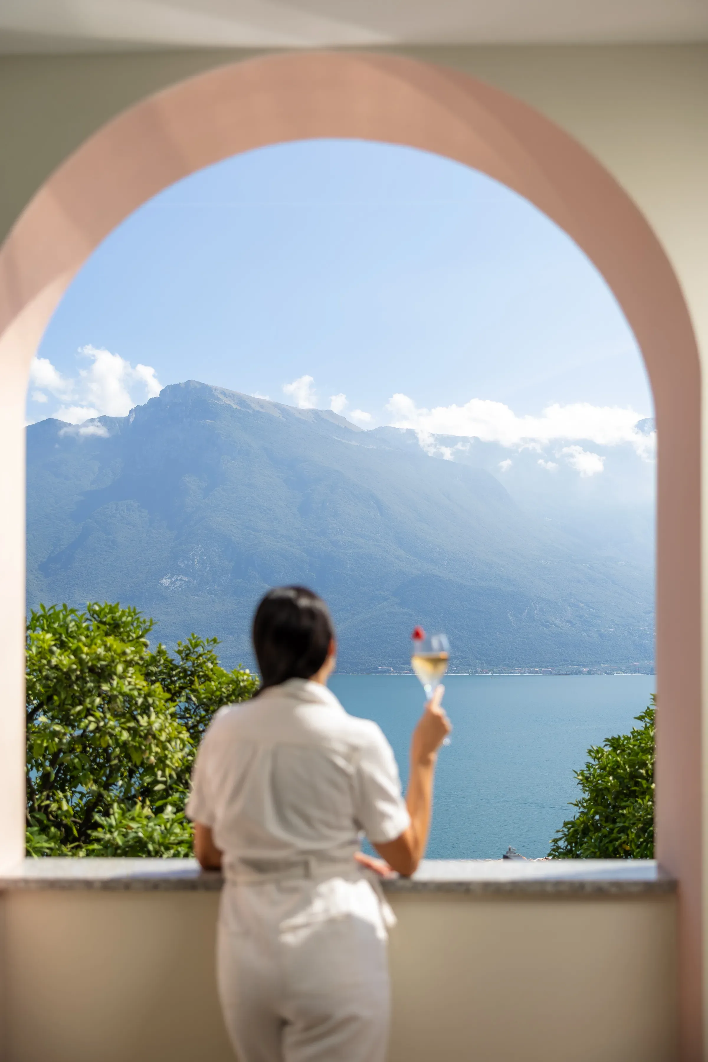 Woman enjoying a drink while looking at a scenic lake and mountains